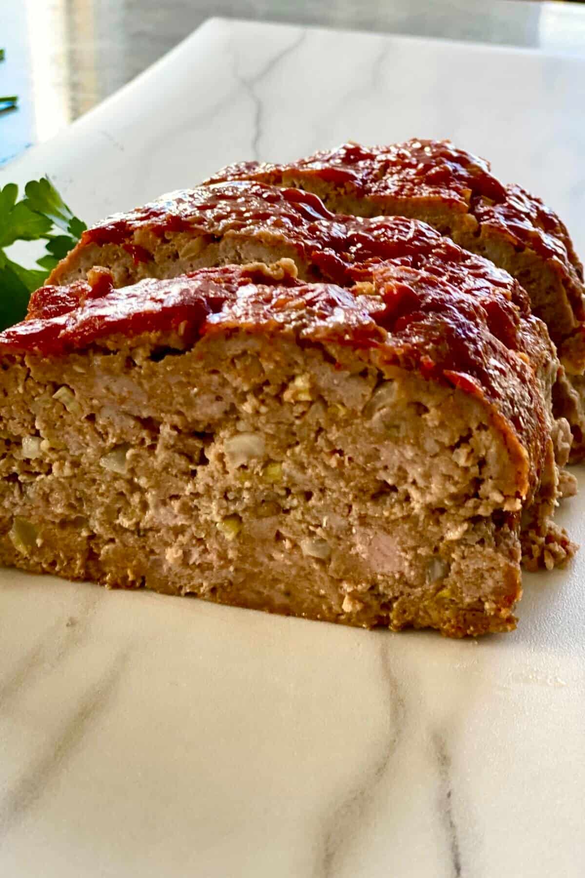 3 slices of mom's meatloaf on a white marble counter.