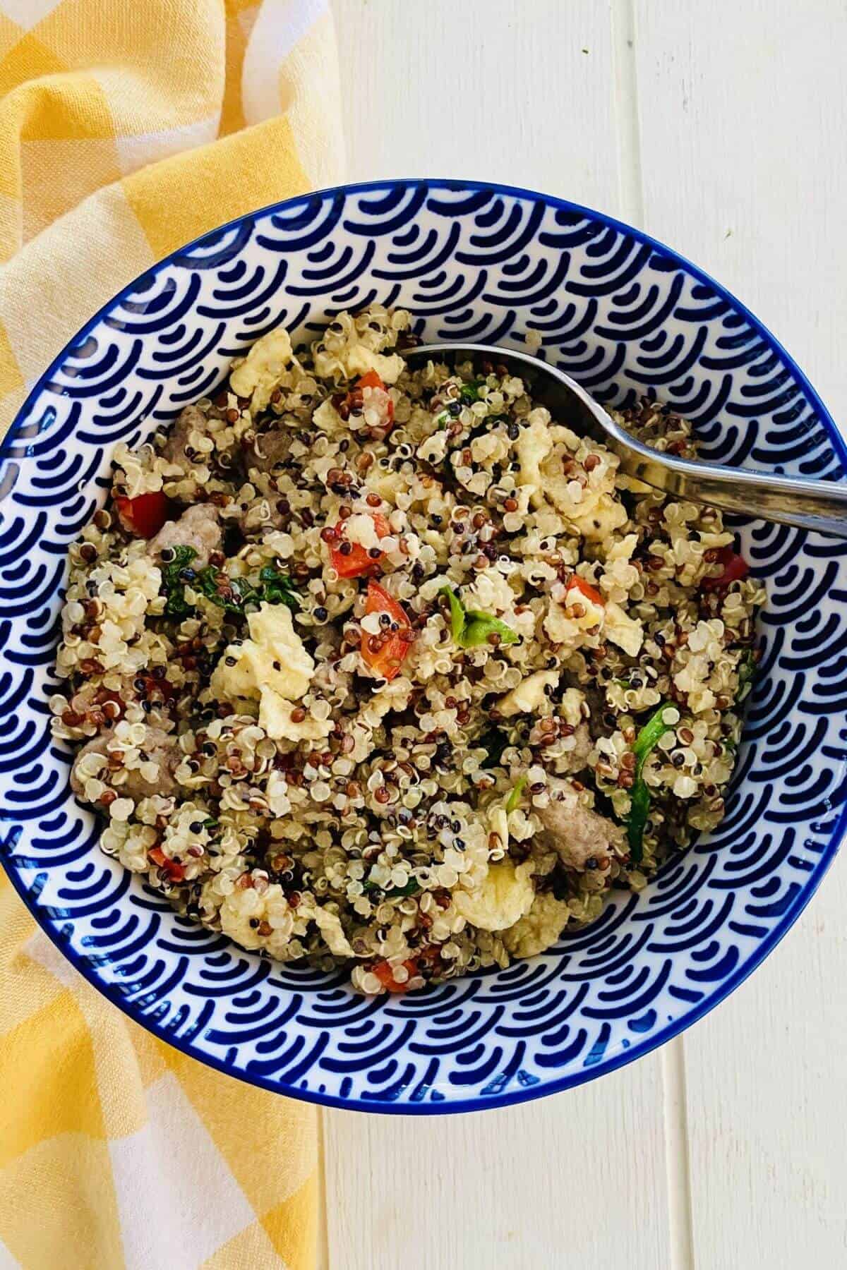 A quinoa breakfast bowl with eggs, bell peppers and spinach.