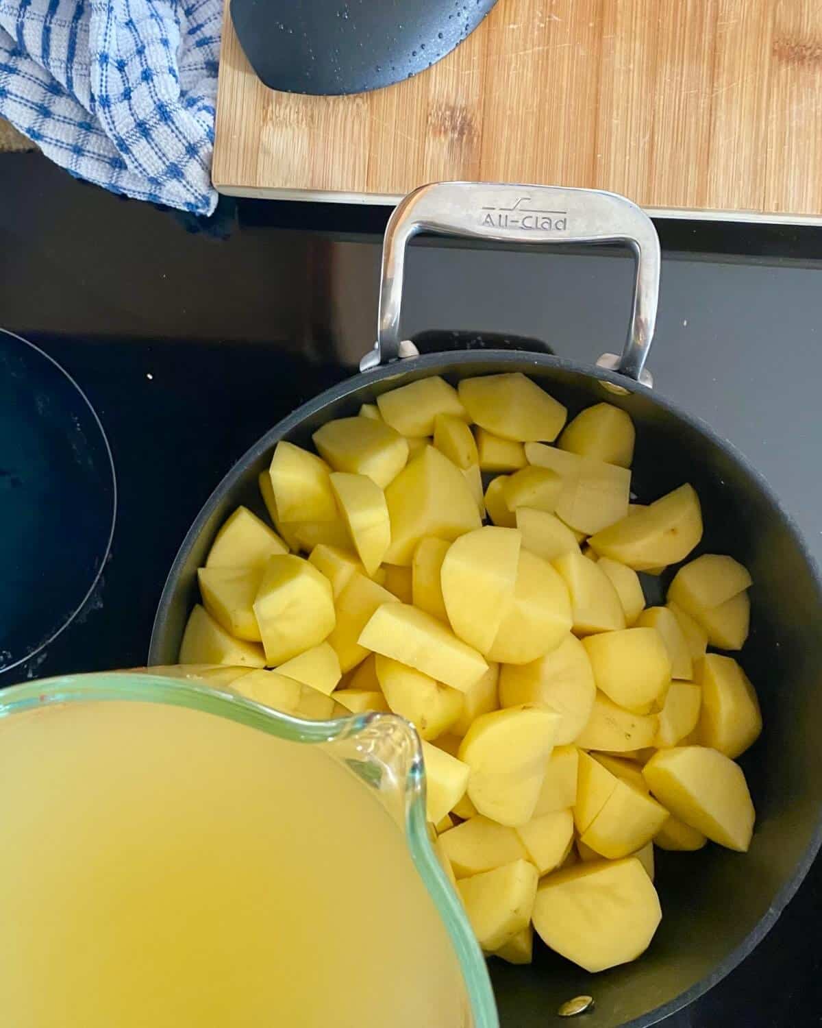 cubed potatoes in a pot and adding chicken stock.