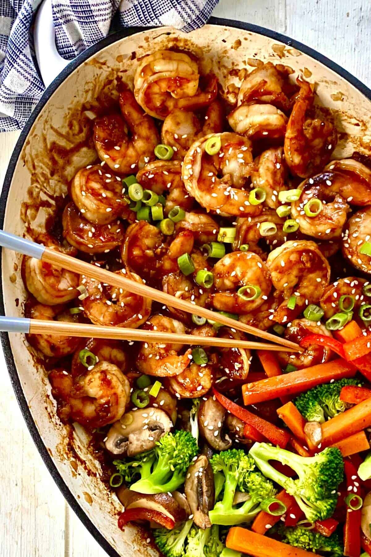 large white pan with hibachi shrimp and vegetables with chopsticks.
