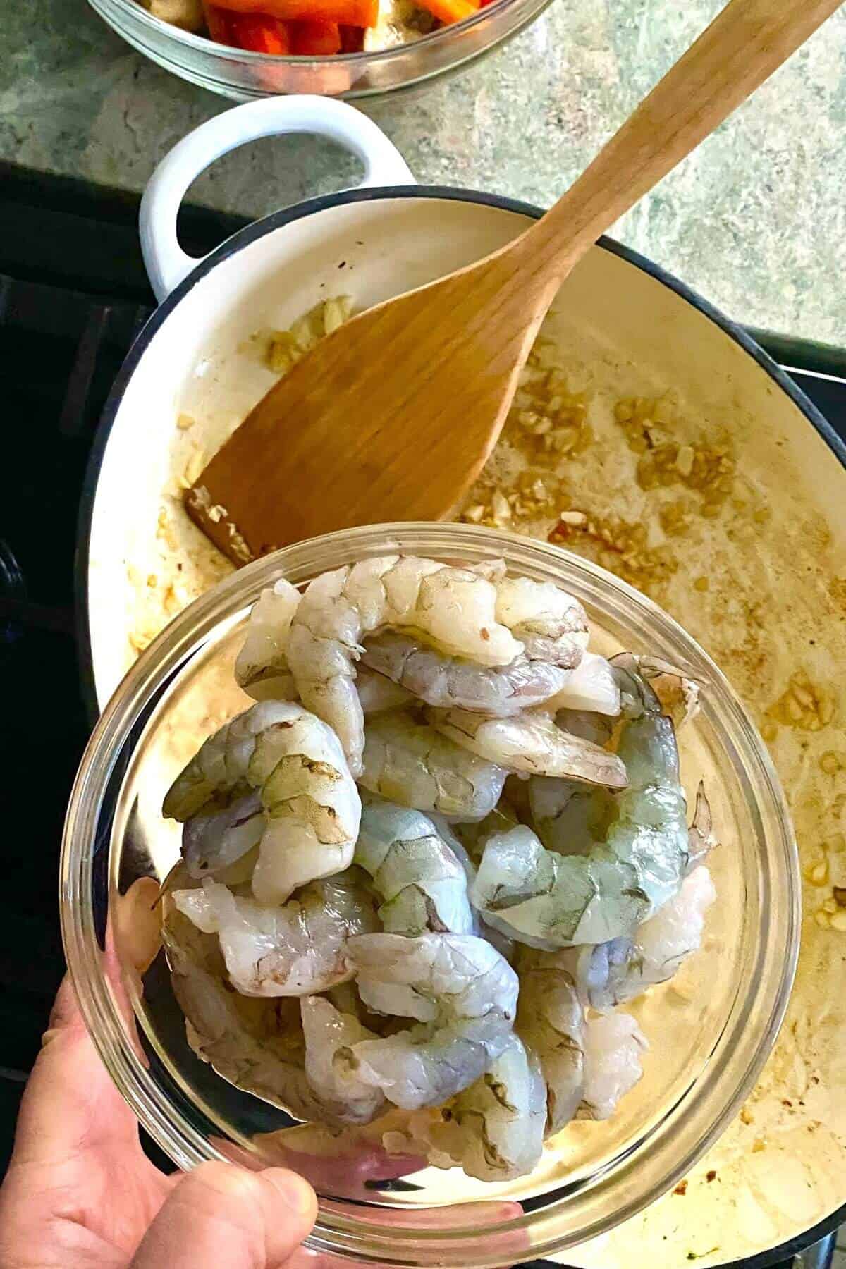 adding shrimp to pan with garlic and ginger root.