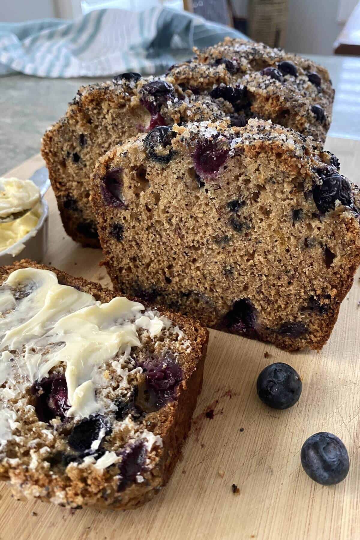 sliced olive oil banana bread with blueberries and butter.