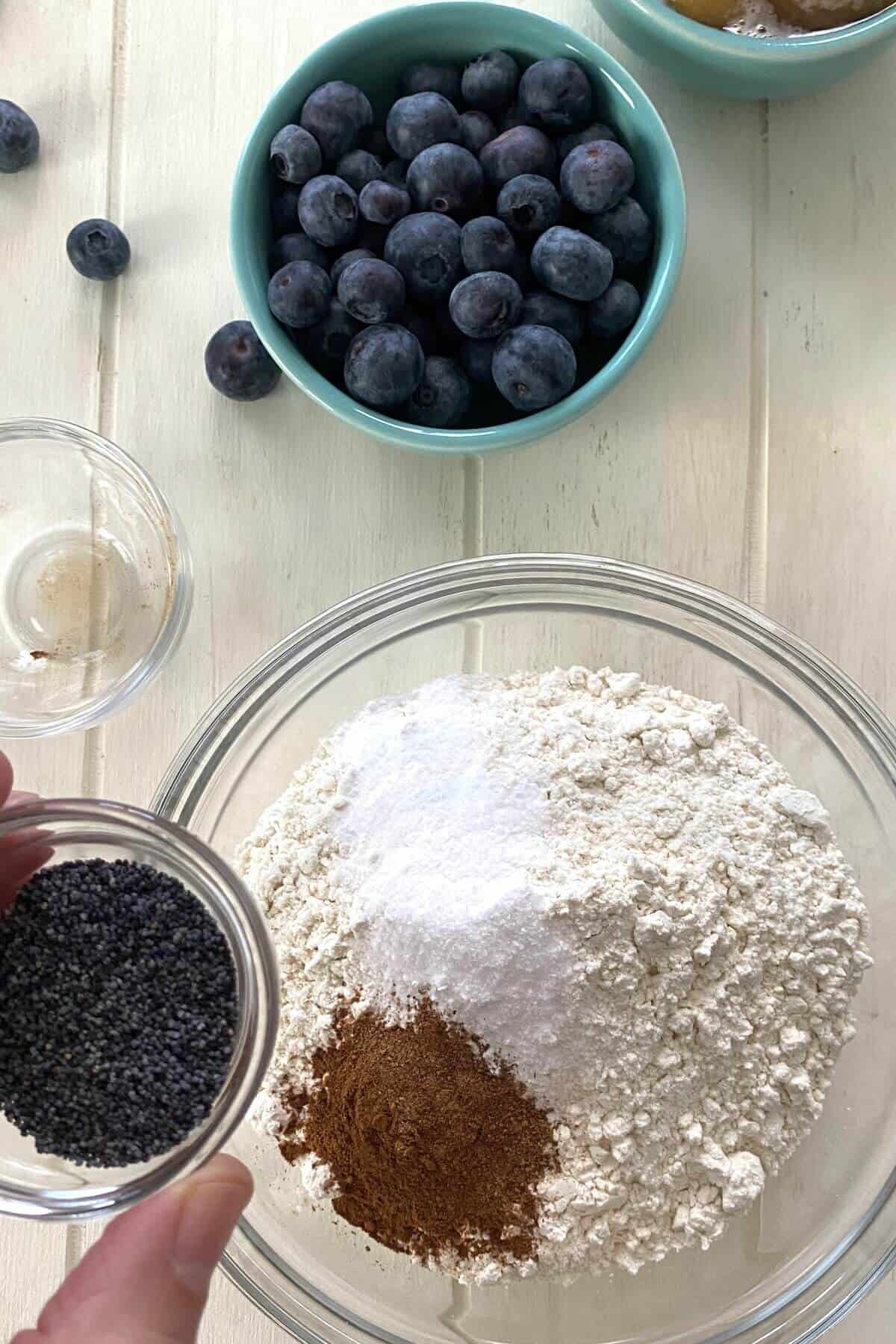 Adding poppy seeds to dry ingredients.