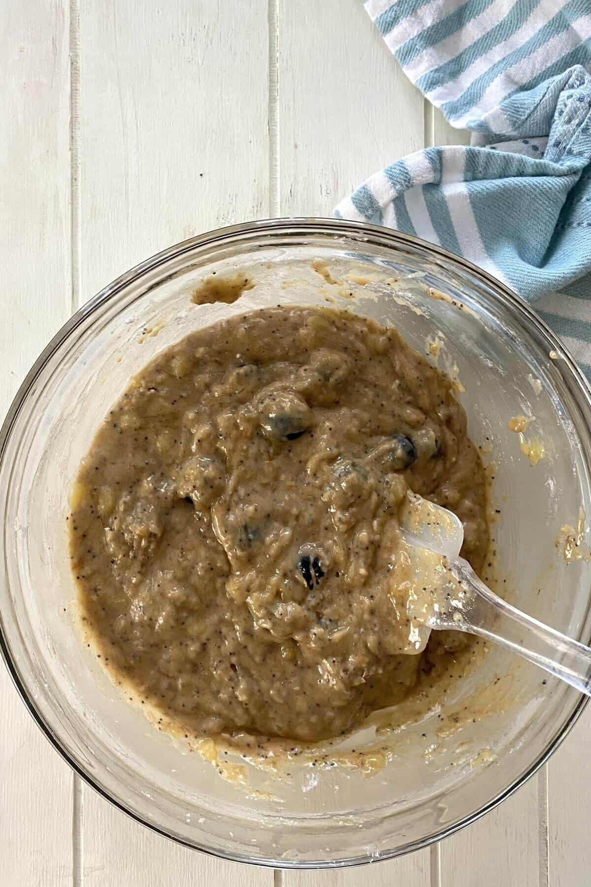 Olive oil banana bread batter in a glass bowl.