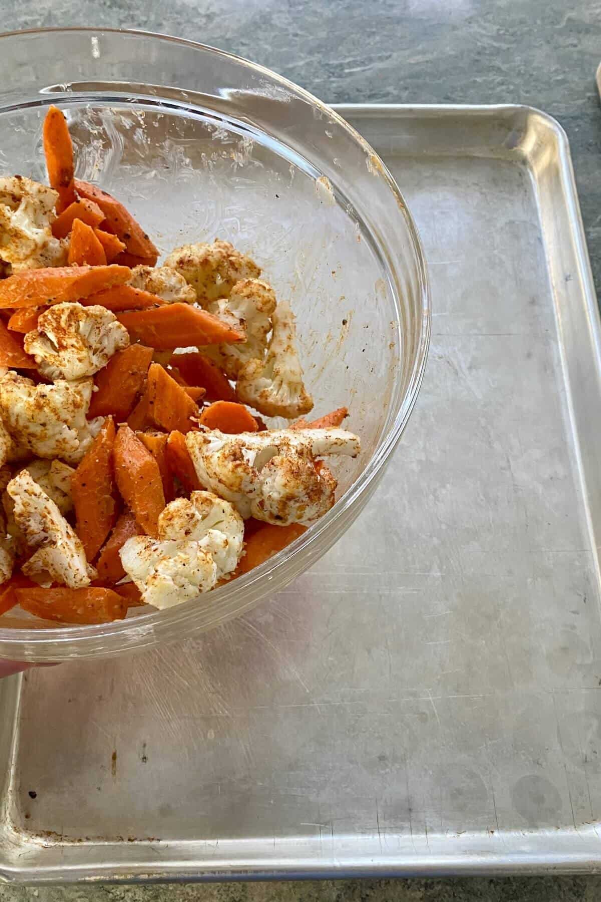 putting seasoned vegetables on a baking sheet.