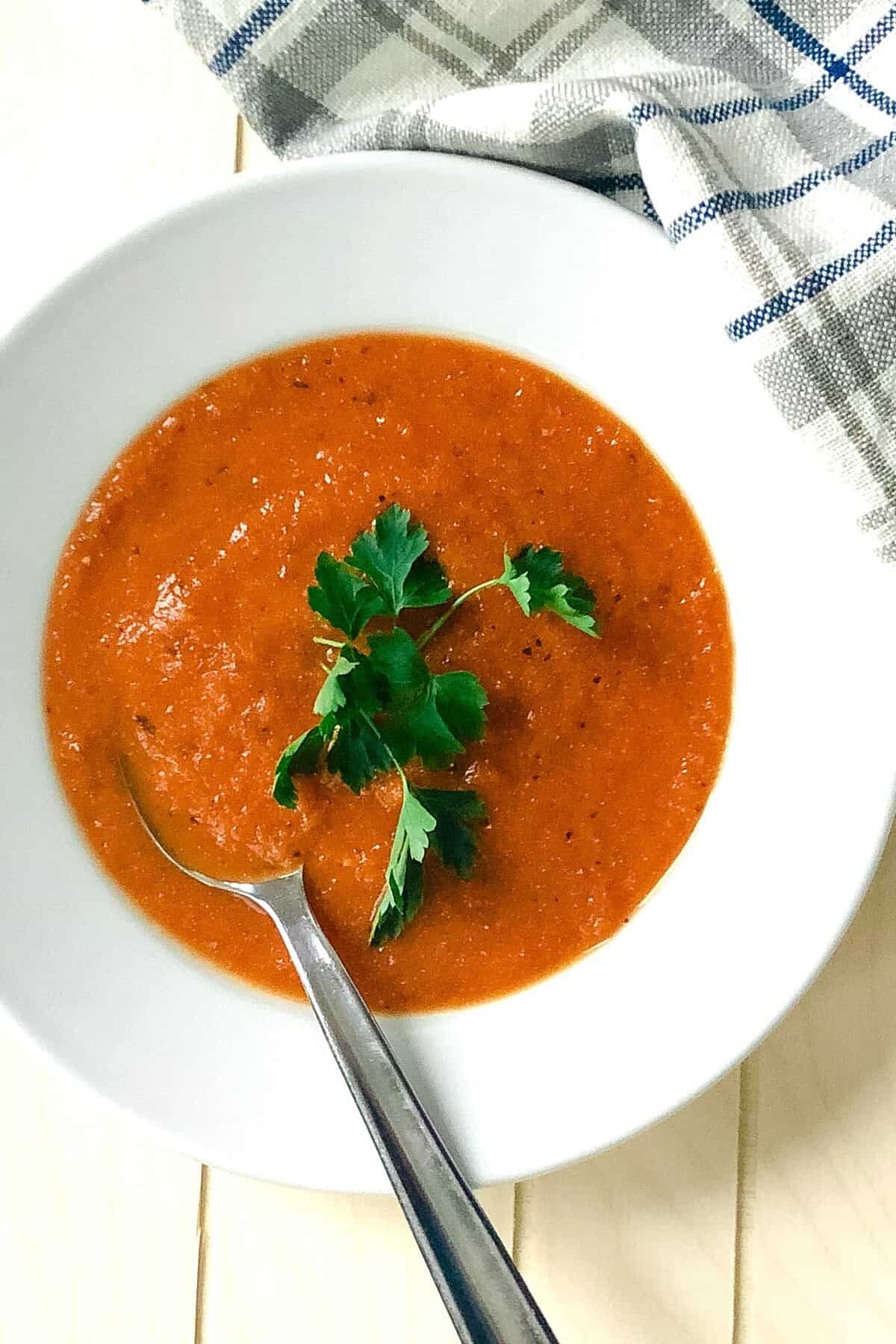 Bowl of creamy roasted tomato basil soup with a soup in it.
