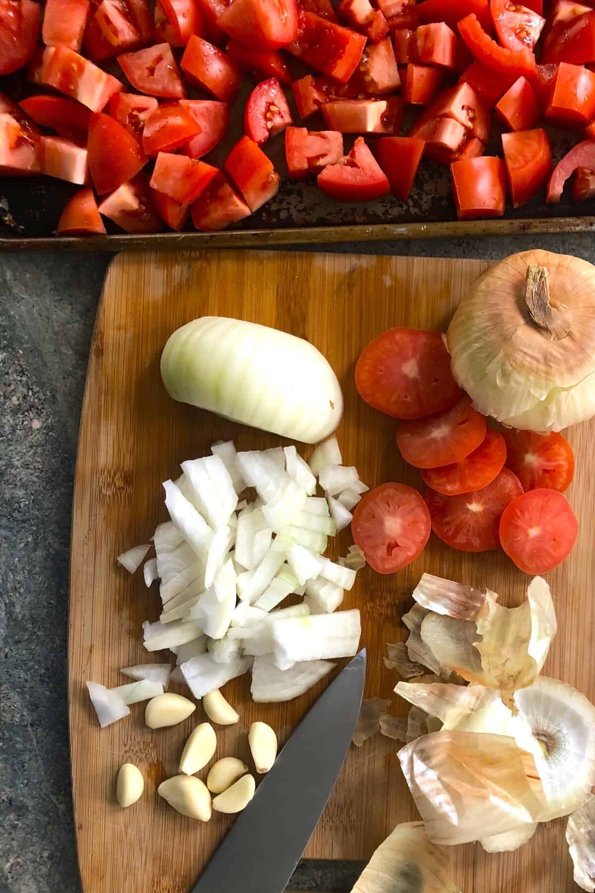 chopped tomatoes, onion and garlic on a baking sheet.