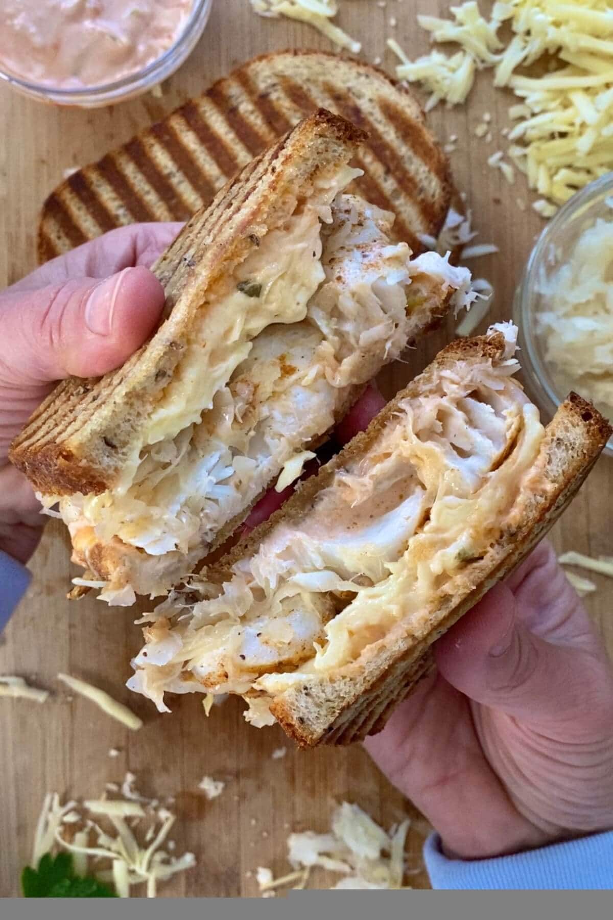 A fish reuben sandwich cut in half.
