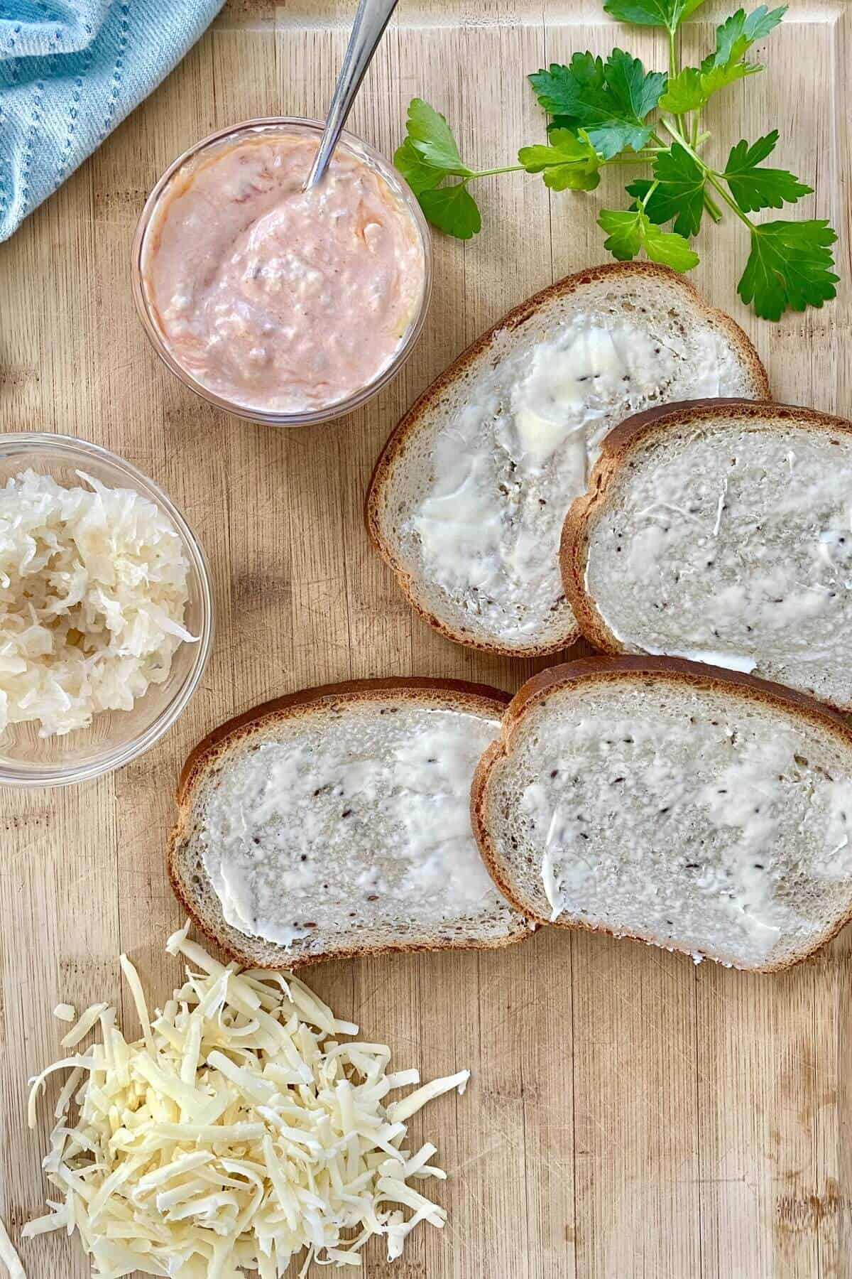 Buttered bread, sauerkraut, shredded cheese for fish reubens.