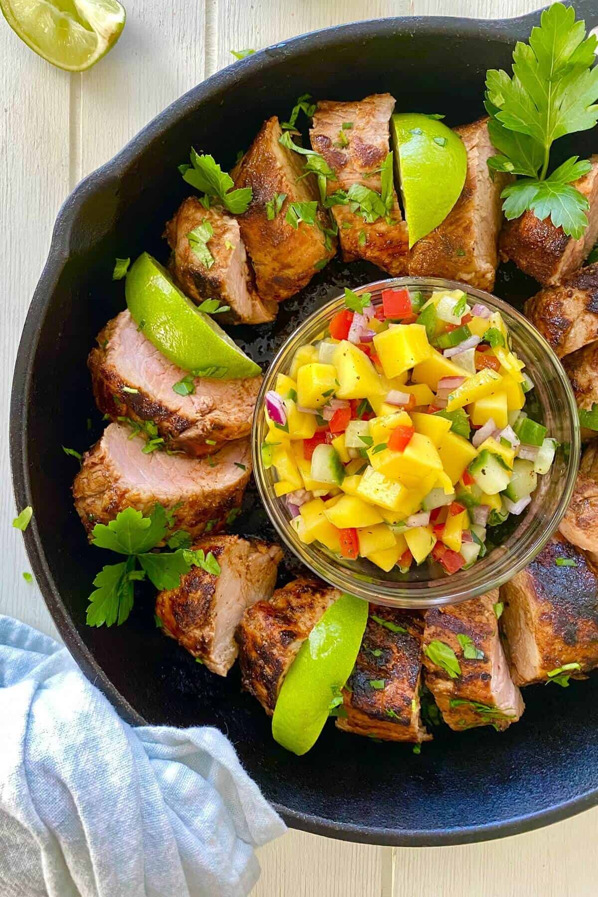 A sliced pork with mango in a cast iron skillet.