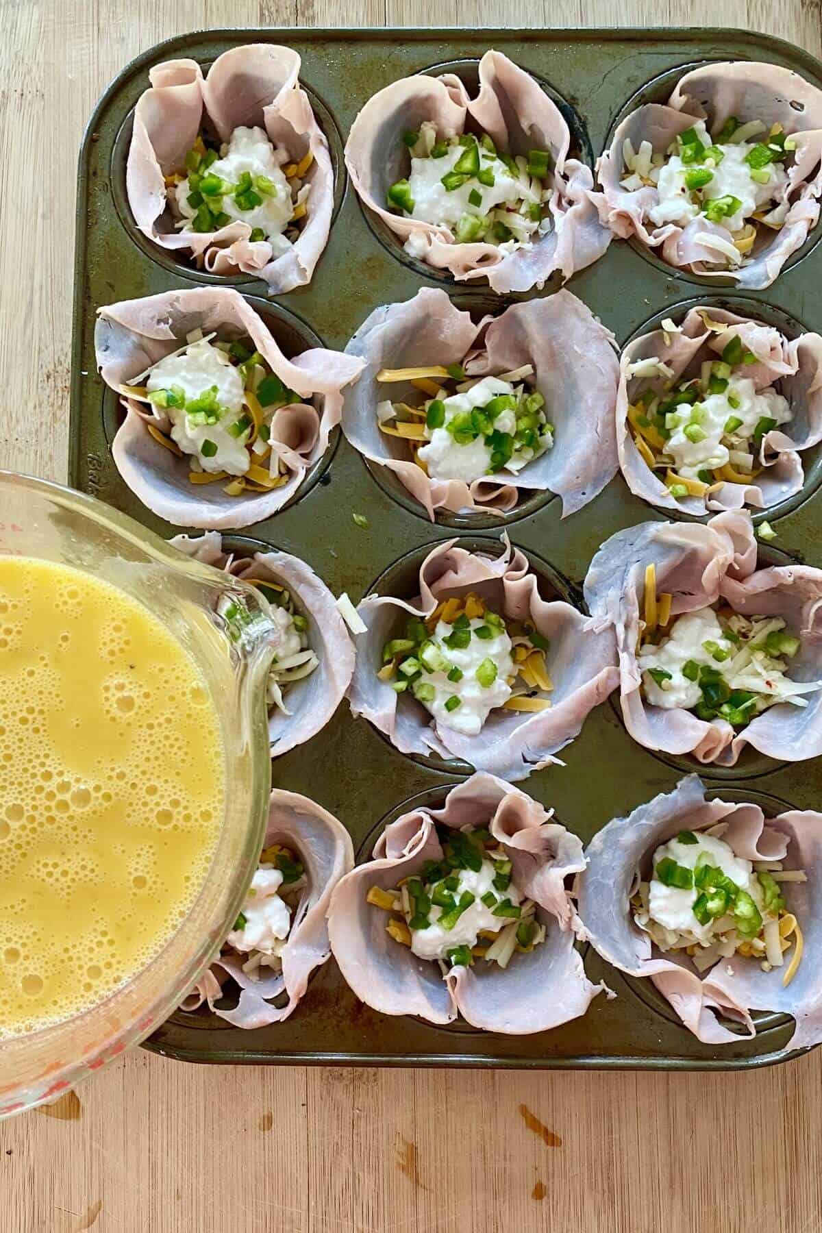 filling egg cups with beaten egg.