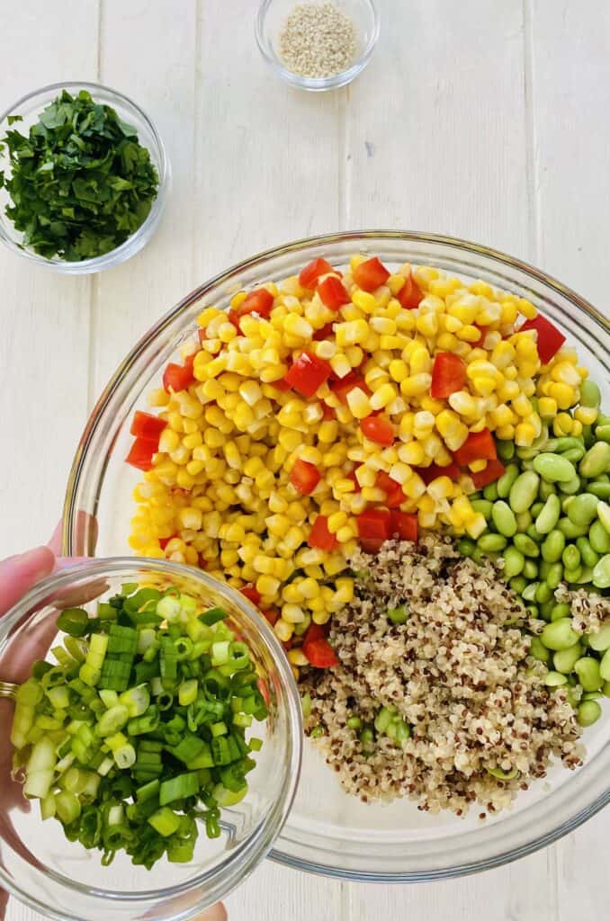adding green onions to quinoa salad.
