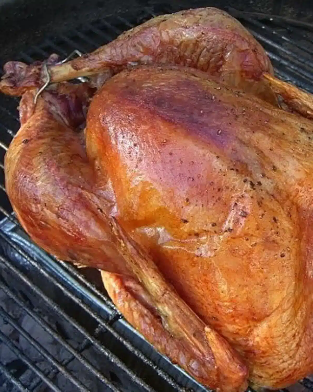 a whole grilled turkey on a Weber charcoal grill.