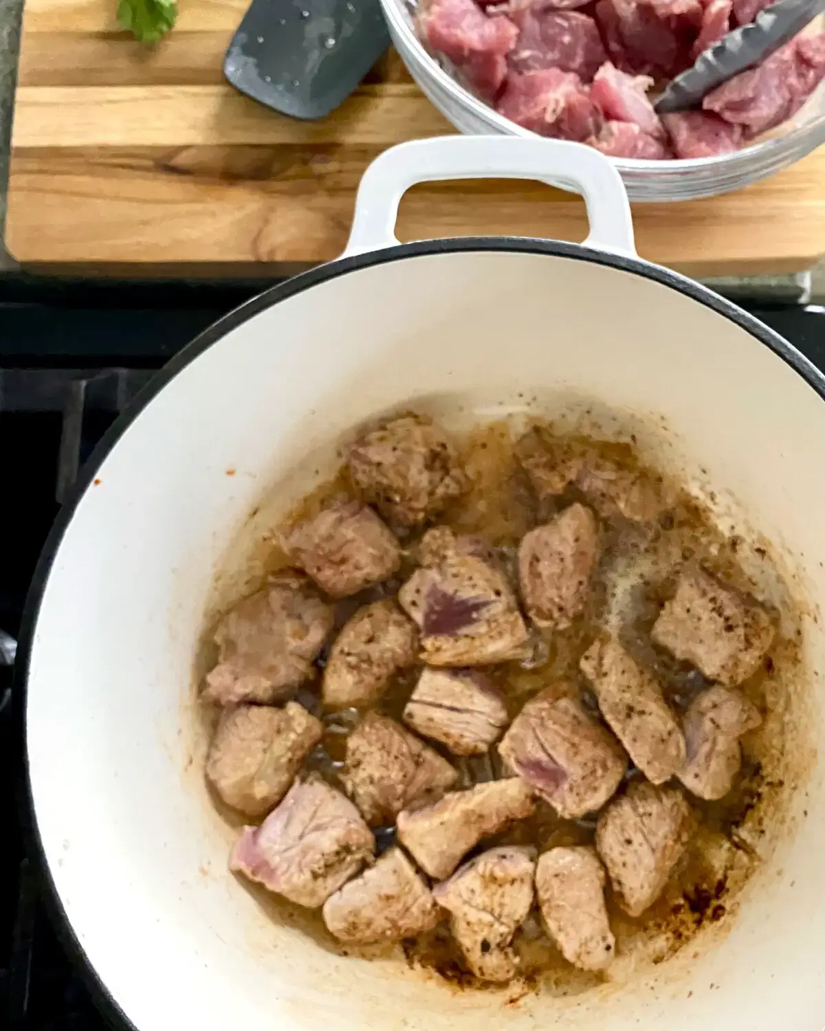Searing pork tenderloin cubes in a Dutch oven.