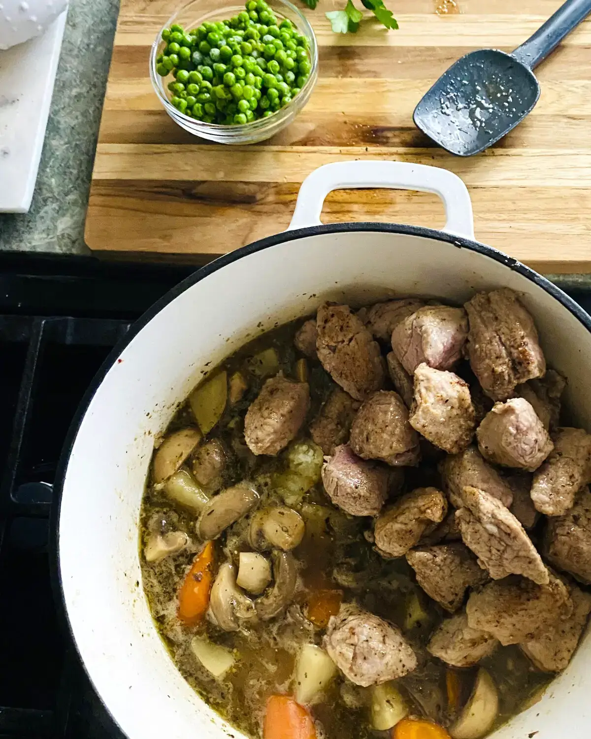 Pork tenderloin cubes in pot with vegetables.