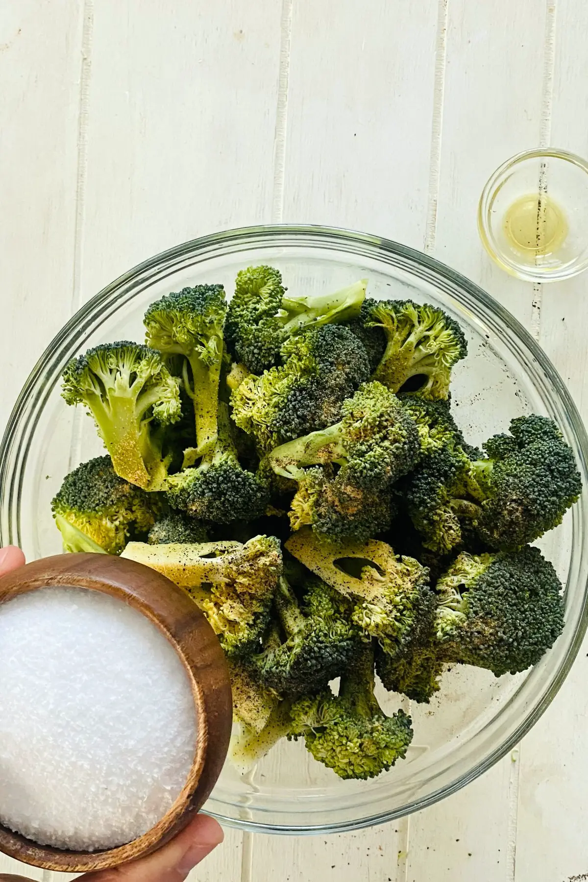 adding kosher salt to raw broccoli.