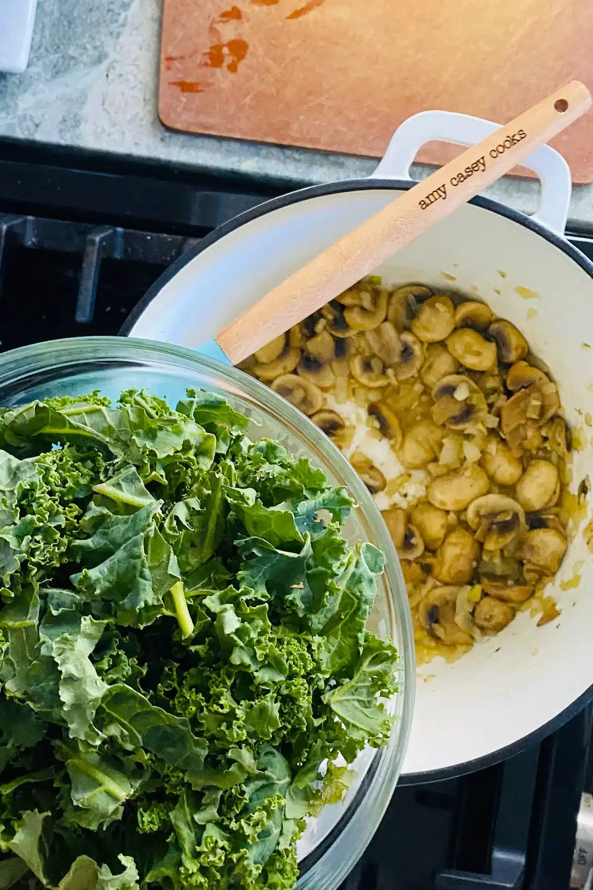kale in a bowl with sauteed mushrooms in a Dutch oven.