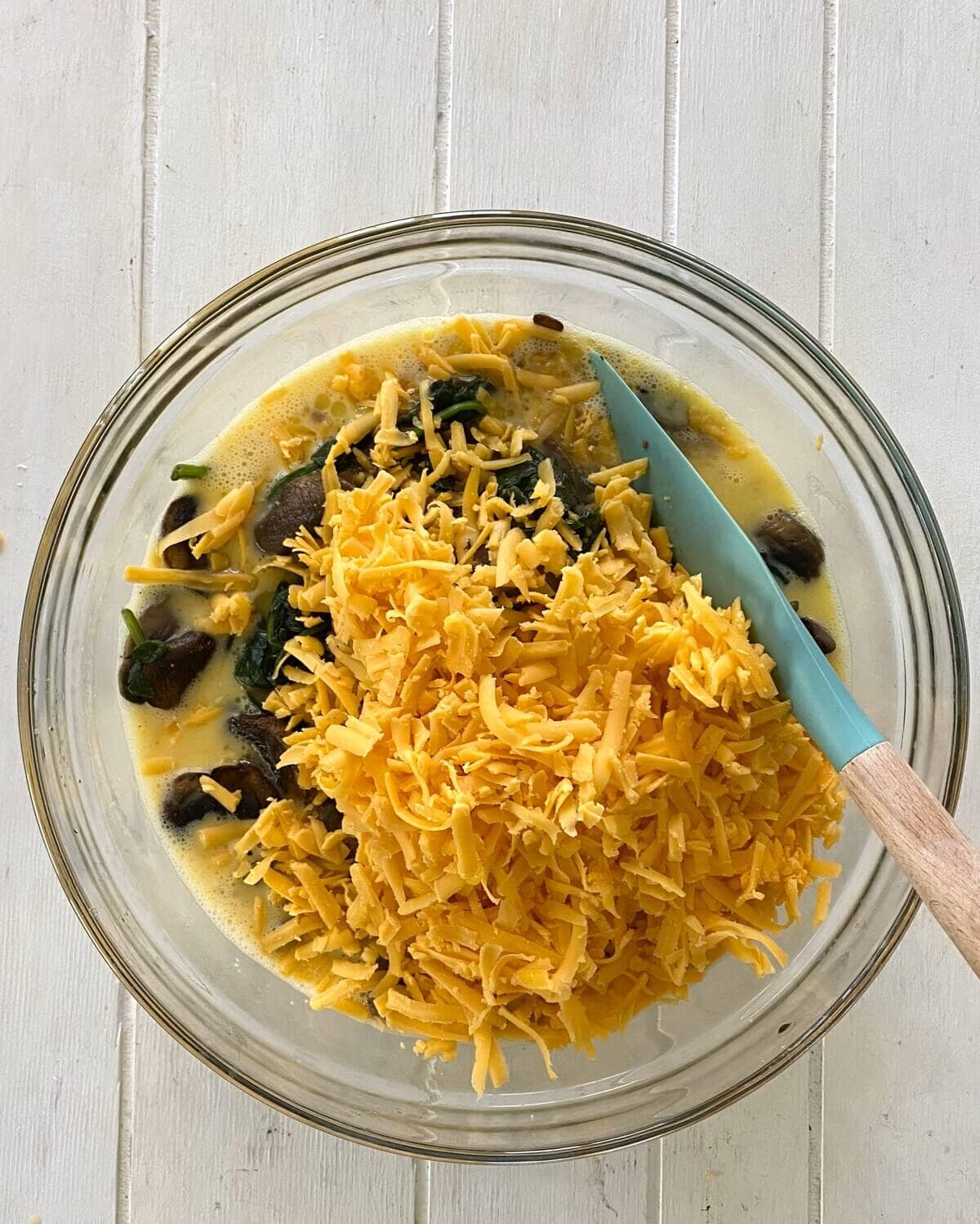 adding shredded cheese to egg casserole.