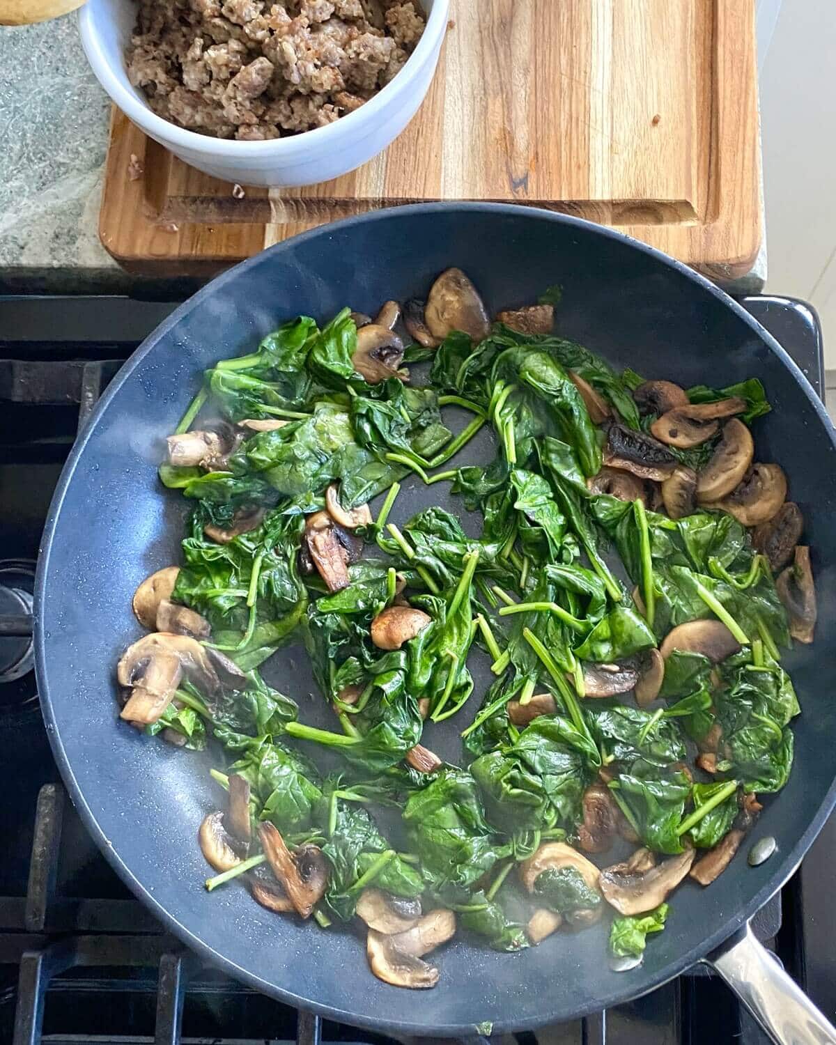sauteed mushrooms and spinach in a pan.