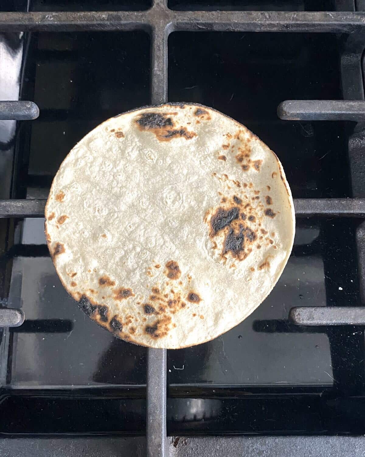 charred corn tortilla on the stovetop.