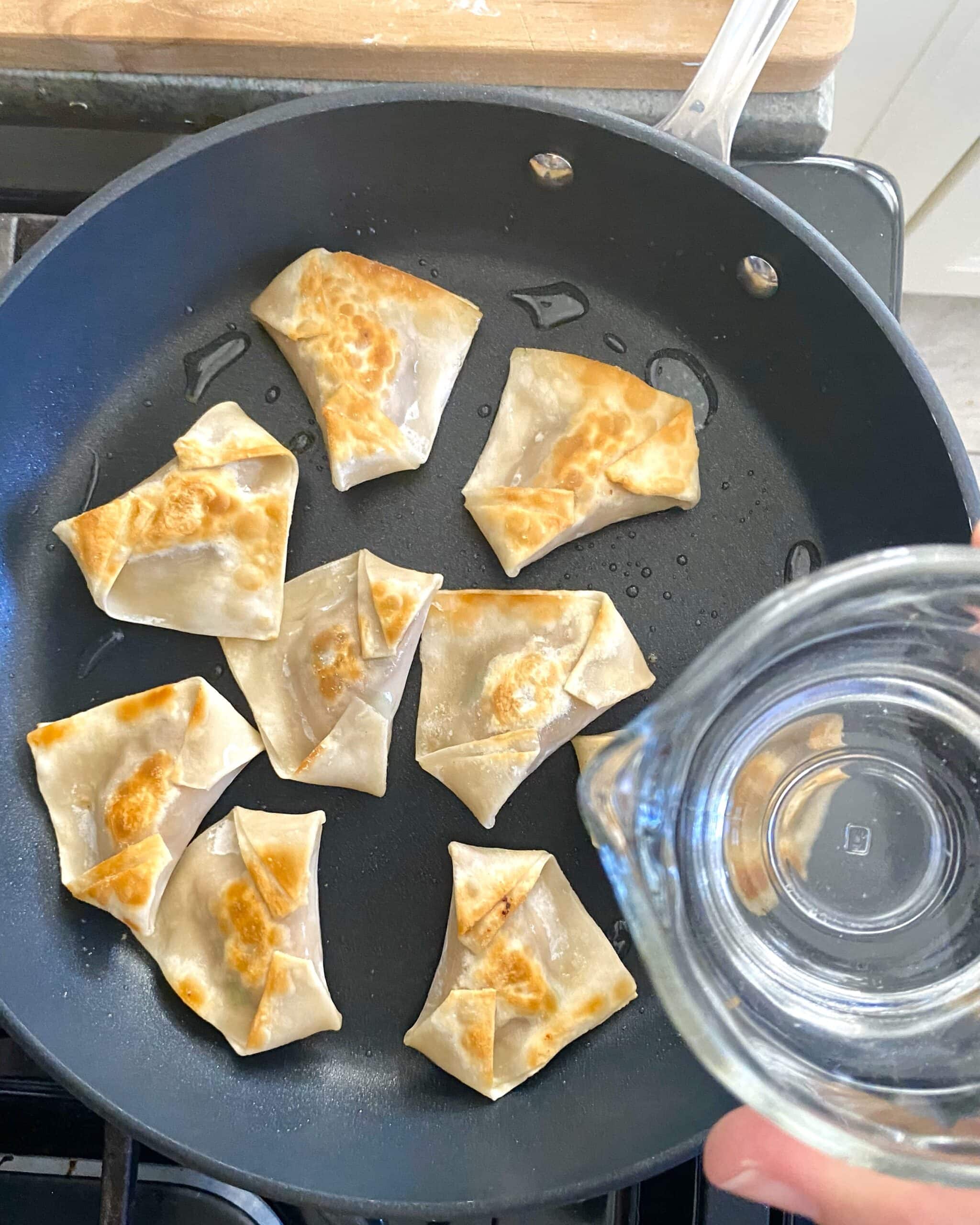 Adding water to pan with potstickers.