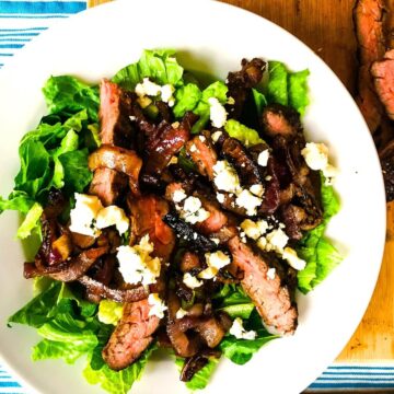 A serving of steak salad with roasted onions and blue cheese.