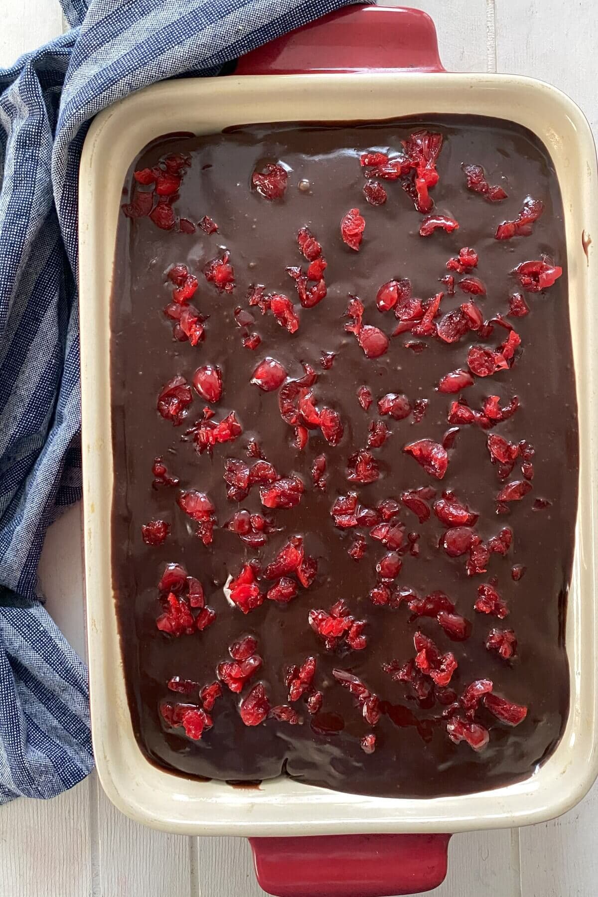 The iced chocolate cake with chopped cherries on top.