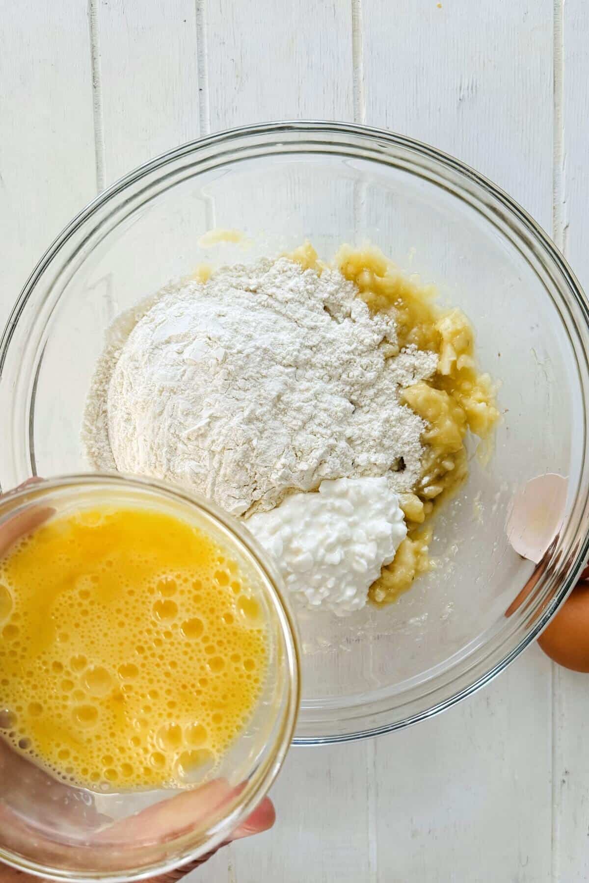 Adding eggs to flour and mashed bananas.