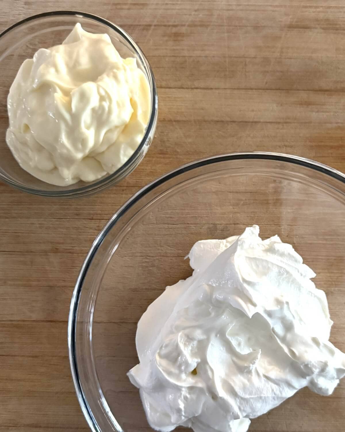 A bowl of mayonnaise and a bowl of sour cream.