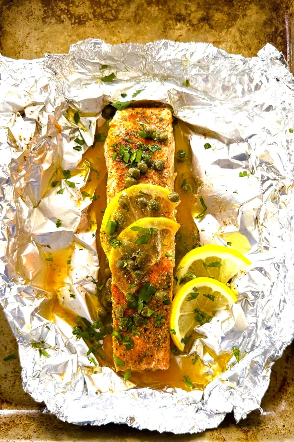 A piece of salmon with lemon and capers.