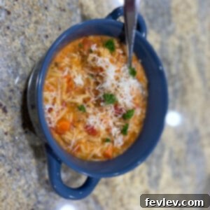 A steaming bowl of hearty Italian Sausage and Orzo Soup, garnished with fresh herbs and Parmesan cheese.