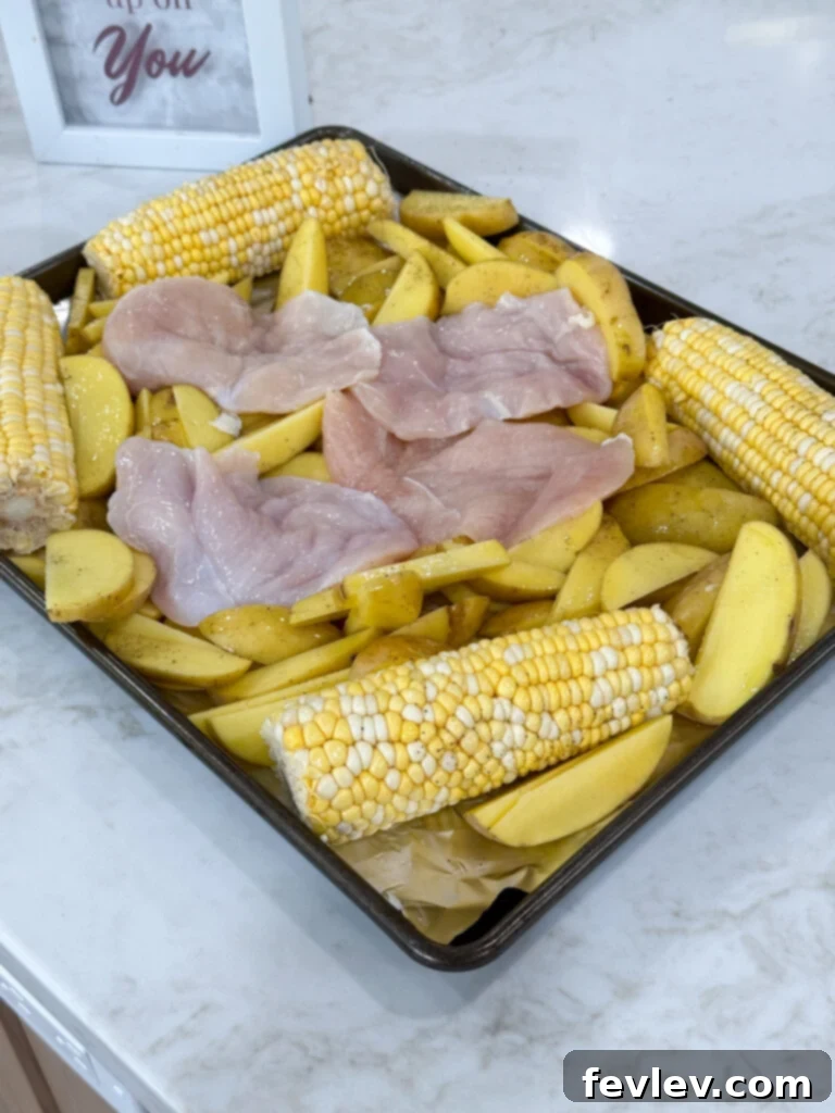 Barbecue Chicken Sheet Pan Feast 3 how to prepare sheet pan bbq chicken - a sheet pan lined with foil with cut potatoes and corn arranged on it