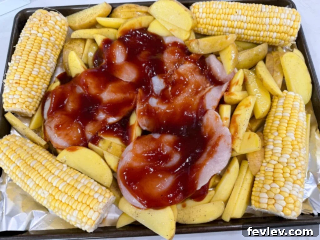 Barbecue Chicken Sheet Pan Feast 5 sheet pan bbq chicken bake - chicken breasts, corn, and potato wedges baking on a sheet pan