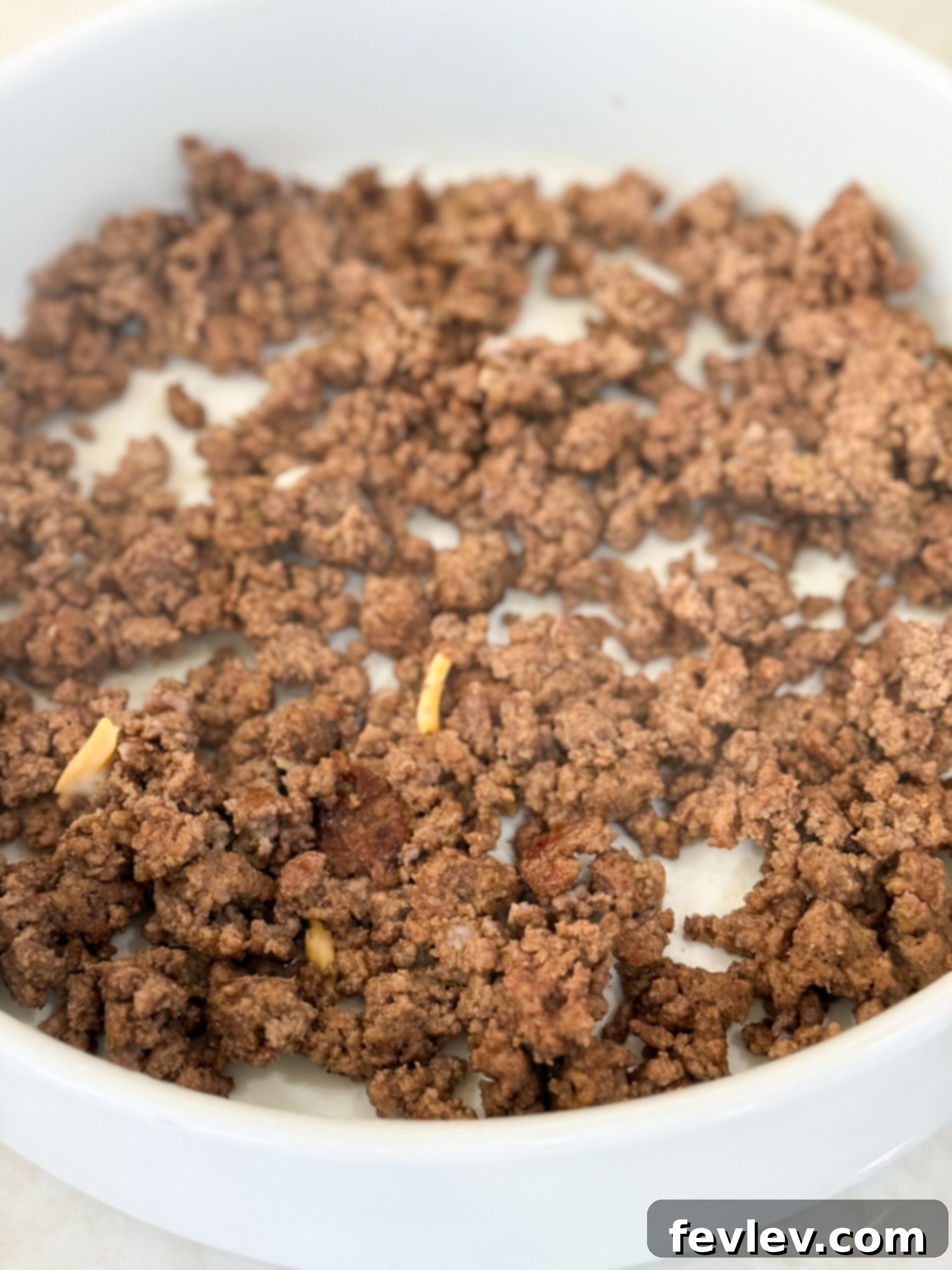 Golden Hashbrown Beef Bake 9 The browned and seasoned ground beef evenly spread across the bottom of a 9x13-inch baking dish, forming the first layer of the casserole.