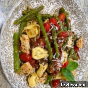 Delicious Sun-dried Tomato Pesto Chicken Tortellini, garnished with fresh herbs and Parmesan
