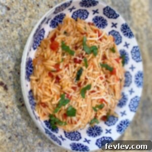 A vibrant bowl of Tomato Basil Parmesan Orzo, garnished with fresh basil, ready to be enjoyed.