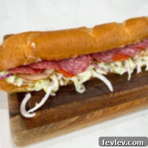 A delicious Italian Grinder Sandwich, piled high with deli meats, melty cheese, and a fresh, tangy salad mixture on crusty bread.