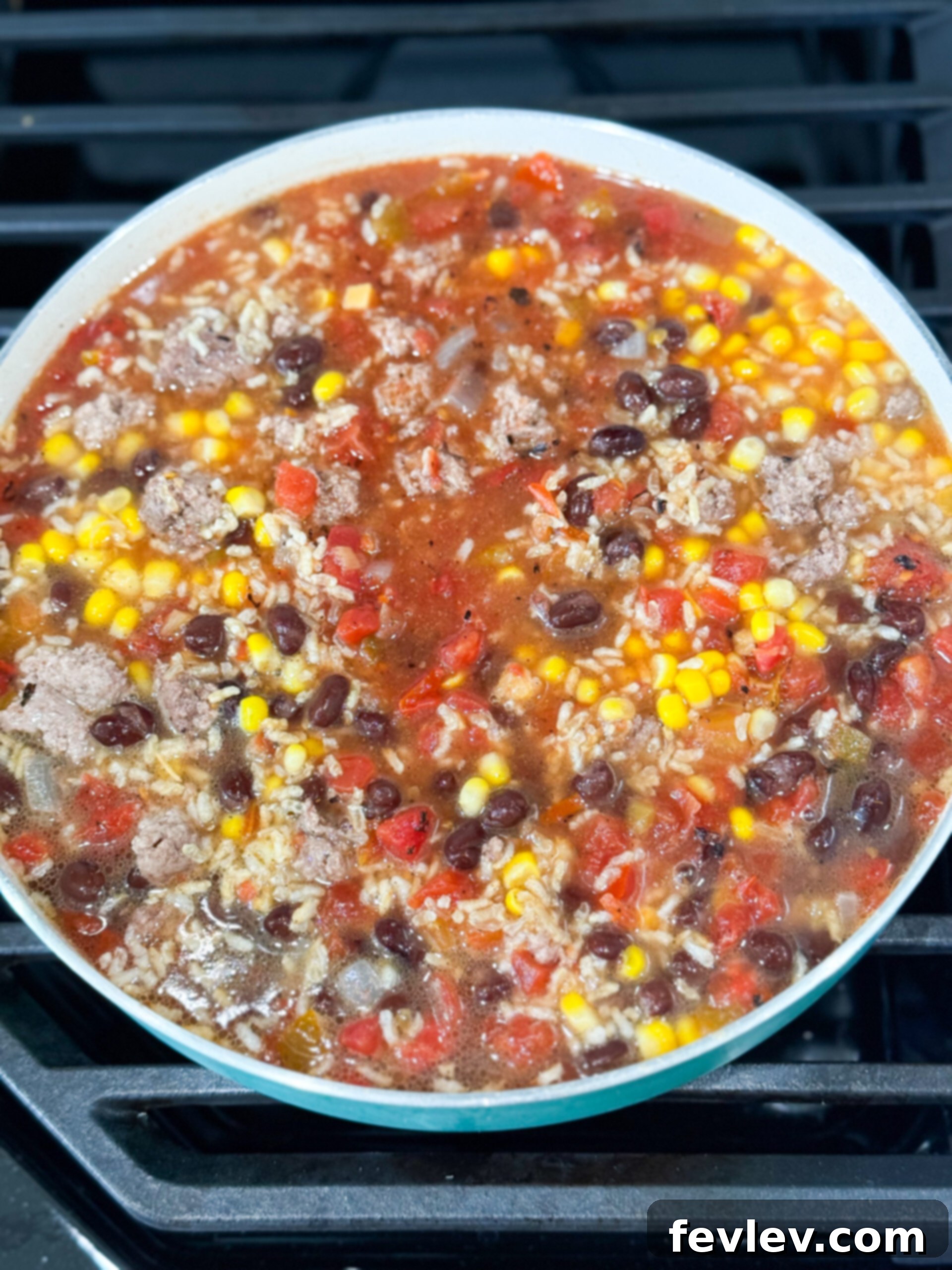 Rice, beans, salsa, and corn simmering together in pot with ground beef and spices