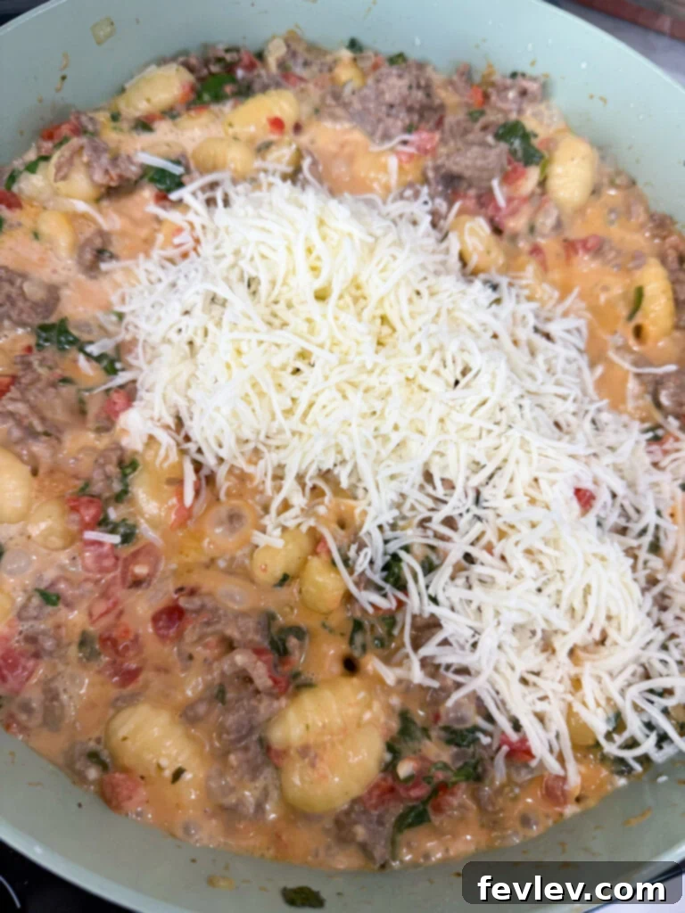 Stirring in mozzarella cheese into the gnocchi and sausage dish