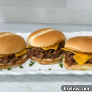 Weeknight Sloppy Joe Winner 7 Simple Sloppy Joe sandwiches with cheese on hambuger buns on a long white plate on top of a white counter