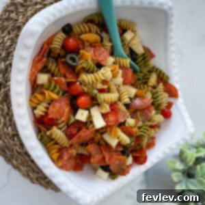 A vibrant bowl of Pepperoni Mozzarella Pasta Salad, garnished with fresh herbs and ready to serve.