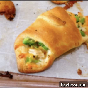 Golden-brown chicken broccoli cheese crescents arranged on a baking sheet, garnished with fresh parsley.