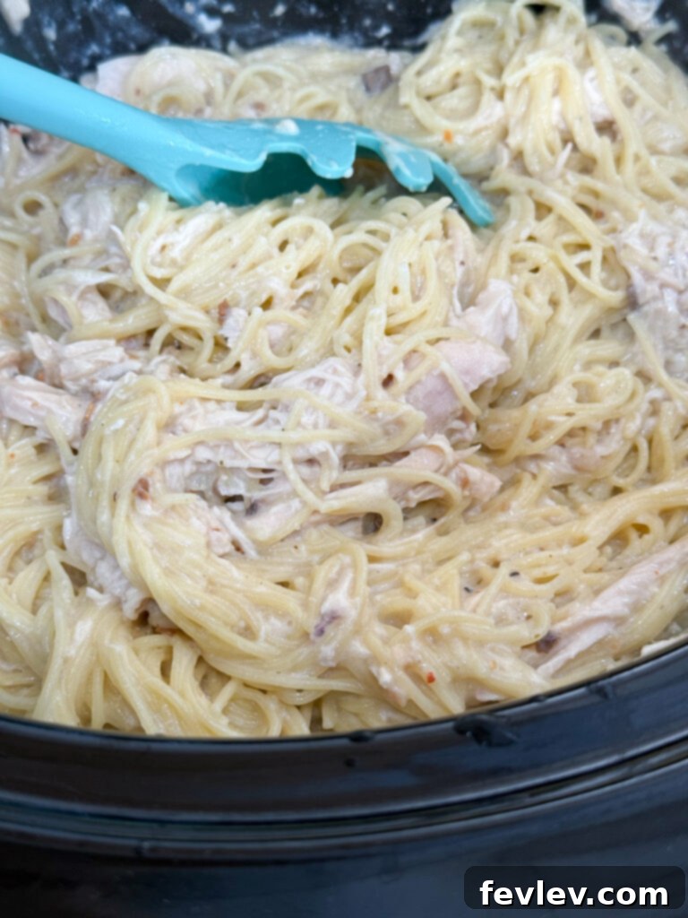 Cozy Slow Cooker Creamy Chicken Pasta 8 Adding cooked pasta to the creamy chicken mixture