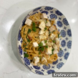 A close-up of creamy Tuscan chicken and pasta garnished with fresh basil.