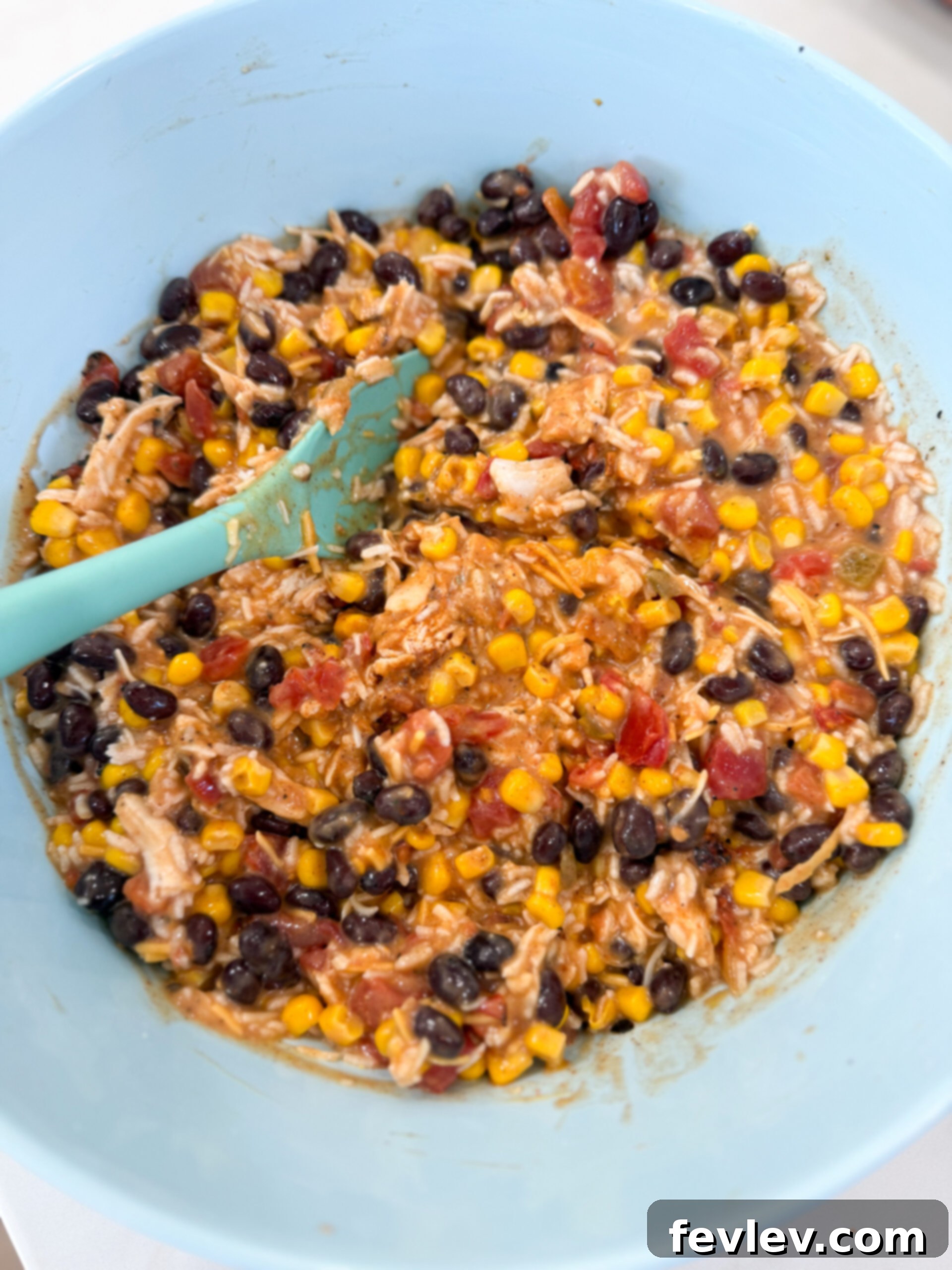 Mixing cooked chicken, instant rice, black beans, corn, Rotel, cream of chicken soup, taco seasoning, and milk in a large bowl for fiesta chicken casserole