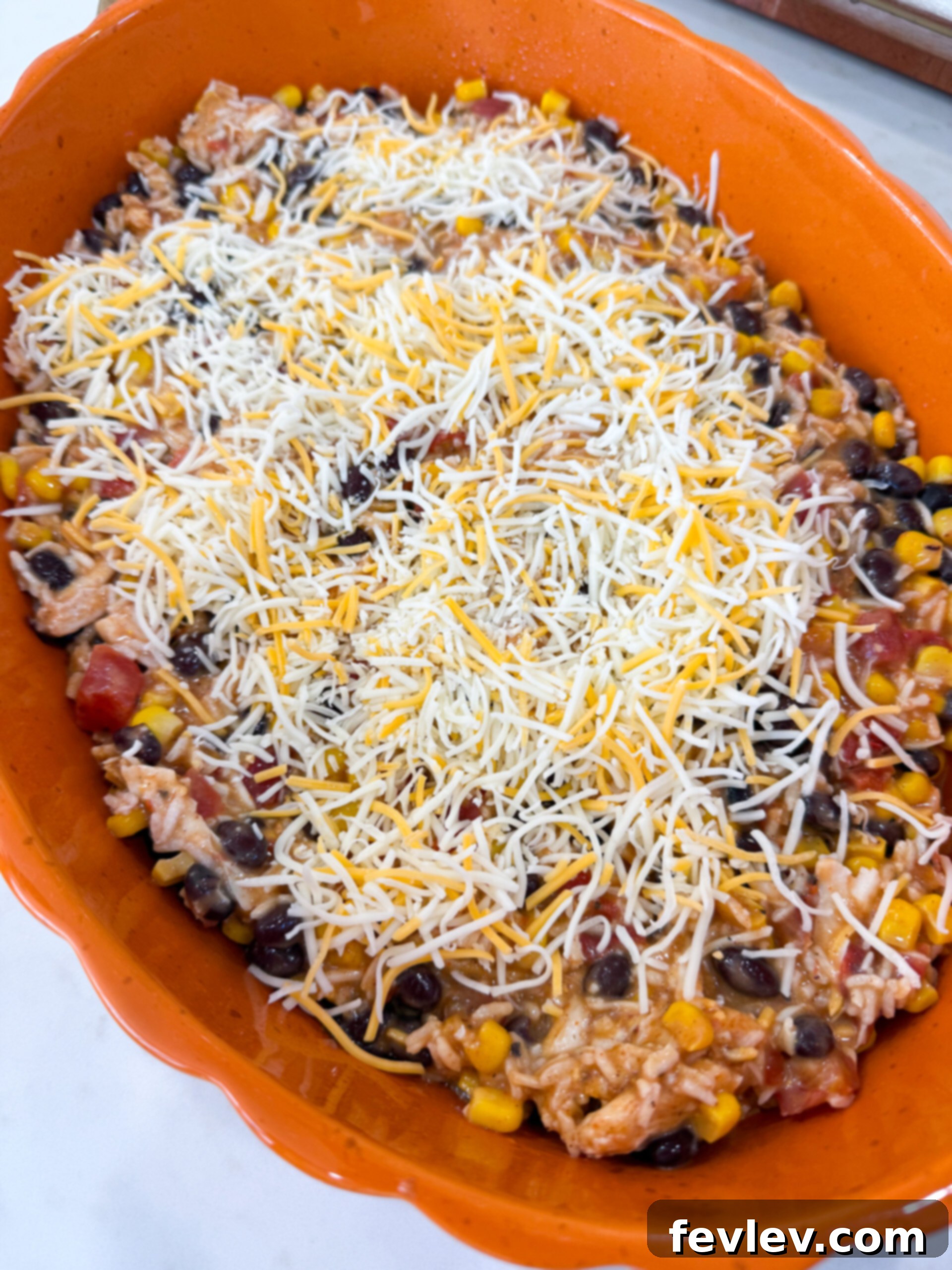 Spreading the mixed fiesta chicken casserole ingredients into a greased 9x13 inch baking dish