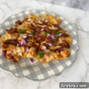 Delicious Sheet Pan BBQ Chicken Nachos on a baking sheet, topped with melted cheese, chicken, red onions, and bacon.