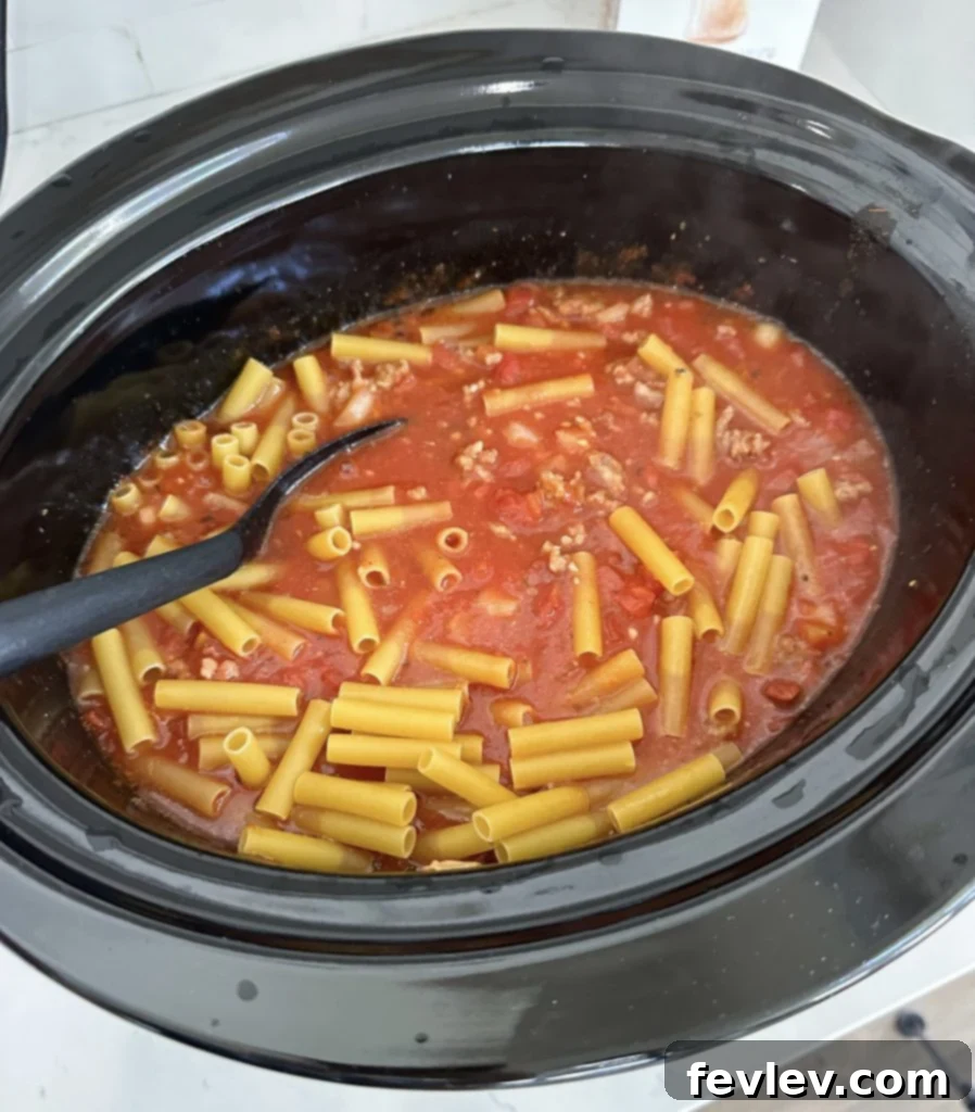 slow cooker filled with baked ziti mixture cooking