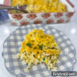 A close-up of a serving of creamy Chicken Noodle Casserole in a small bowl, garnished with fresh herbs.