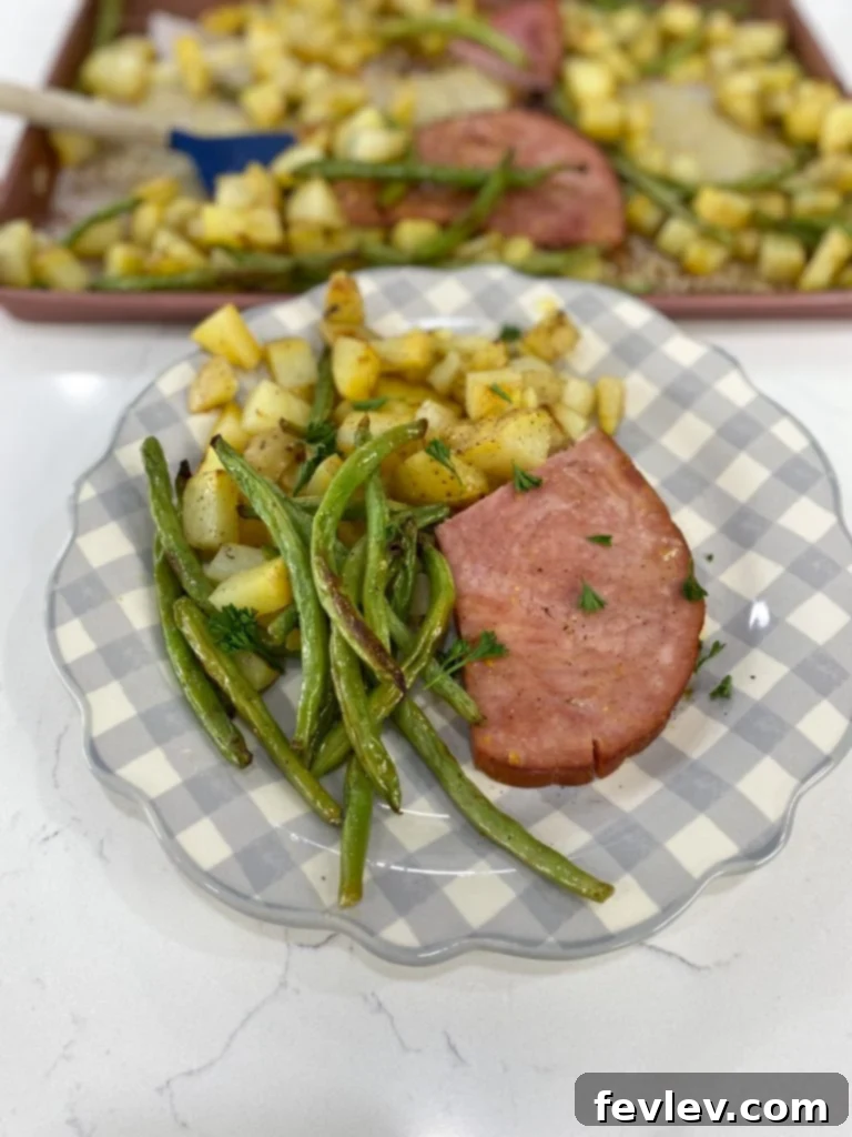 Golden Honey Mustard Ham with Roasted Green Beans and Potatoes 3 Close-up shot of roasted golden potatoes and fresh green beans on a sheet pan, lightly seasoned and ready for the oven.